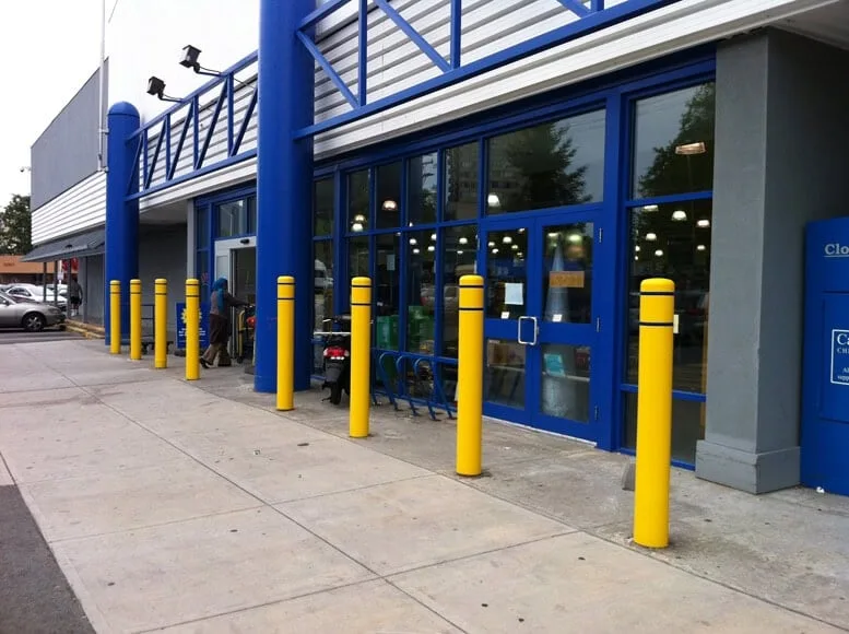 Steel security bollards with decorative covers installed in front of a retail storefront to stop ram-raids